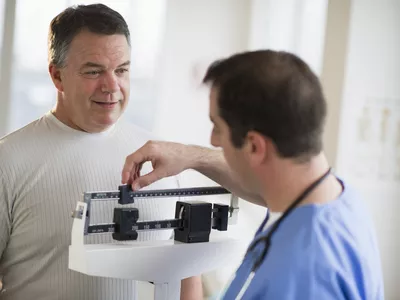 older man getting weighed by doctor