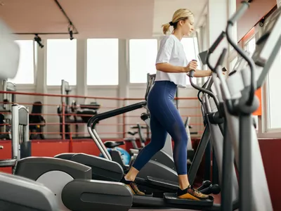 Young woman running and exercising on treadmill in gym. She wears sport clothes and looks attractive.