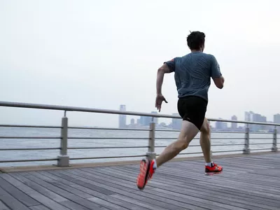 Man running on pier in front of city skyline