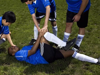 Soccer player down on the field holding his knee in pain