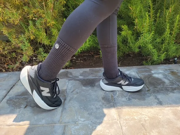 Closeup of a person walking wearing leggings, New Balance sneakers, and lululemon socks on a tiled sidewalk.