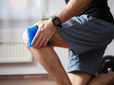 Close-up Of A Person Applying Ice Bag On An Injured Knee In The Gym