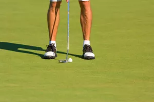 view of man's leg putting on golf course