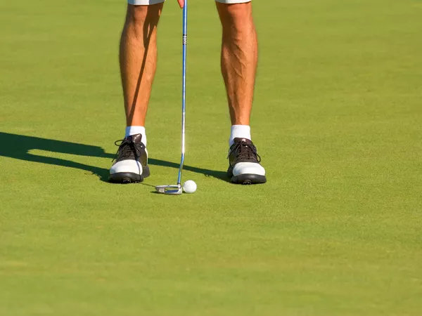 view of man's leg putting on golf course