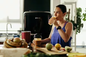 Yong sportswoman drinking fruit juice she made in a blender at home.