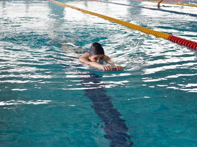 A young girl swims in the pool with a supporting Board for practicing smooth movement on the surface of the track.