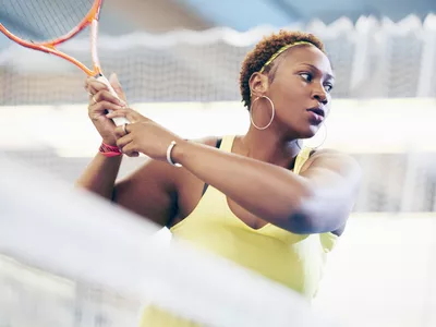 Sports woman on tennis court swinging racket