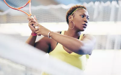 Sports woman on tennis court swinging racket