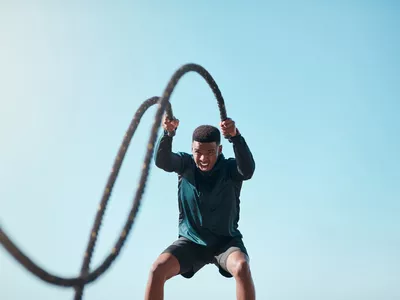 Cropped shot of a handsome young man using battle ropes during a high intensity workout outdoors