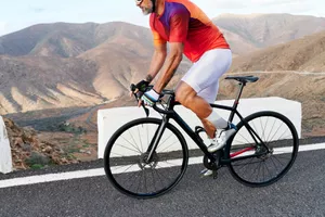 Fit mature man in cycling gear riding his bike on a road through some scenic mountains