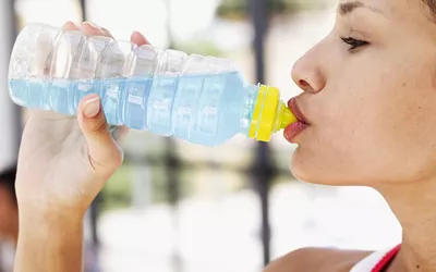 Side profile of a woman drinking blue water from a bottle