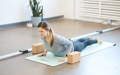 A person practicing yoga on Alo Yoga Warrior Mat