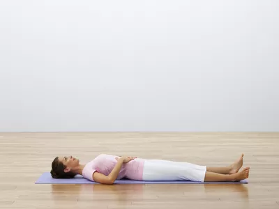 Woman lying on back on yoga mat with hands on abdomen