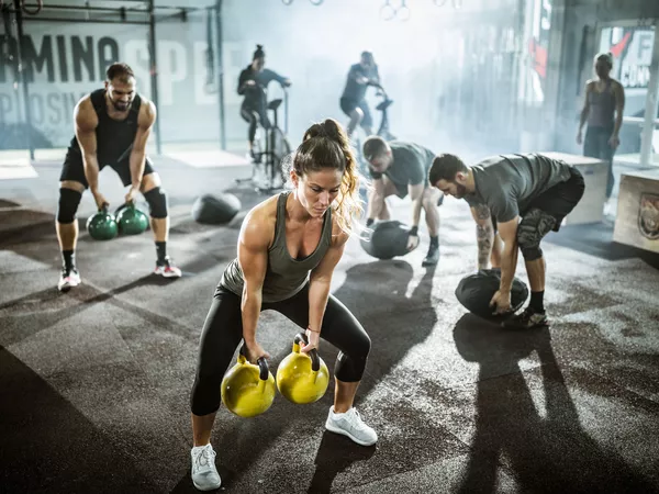 People performing workouts in gym group setting with kettlebells