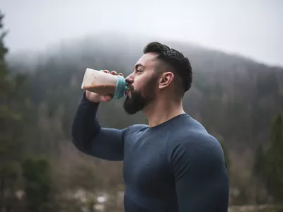 man drinking protein shake while hiking