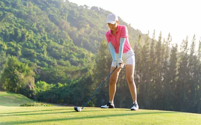 Professional golfer asian woman approach on tee off for swing and hitting golf ball and looking fairway in course. Hobby holiday and vacations in sunny morning day on club golf.