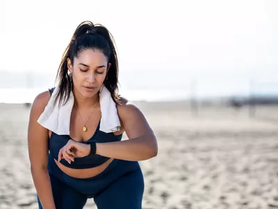woman checking fitness watch while working out on beach