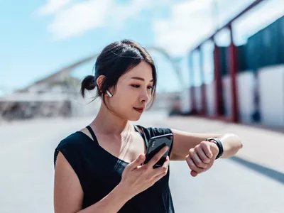 Young women wearing earbuds and holding phone