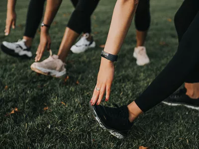Women stretching ankles outdoors in athletic gear
