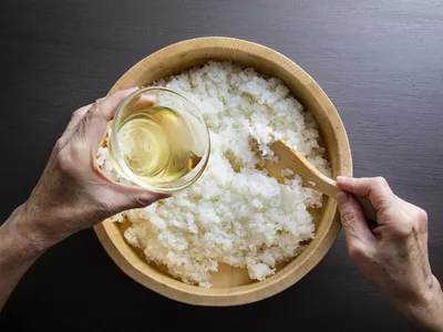 Pouring rice vinegar into a bowl of white rice