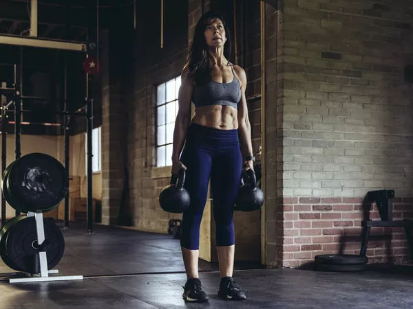 Woman holding kettlebells for farmer's carry