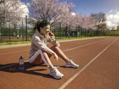 Young woman on track eating an apple