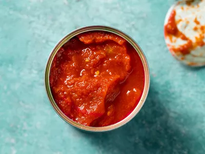 can of tomato sauce, open, on blue countertop