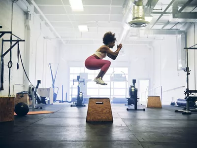 woman jumping onto plyo box