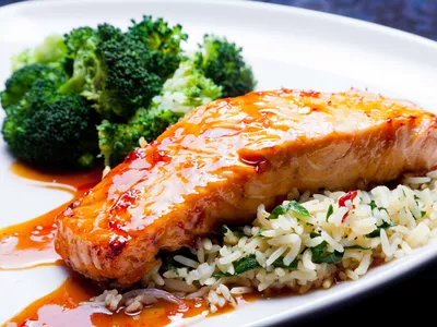 Glazed salmon served with a bed of rice and steamed broccoli