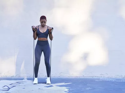 woman performing resistance band workout outdoors in blue