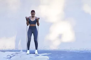 woman performing resistance band workout outdoors in blue