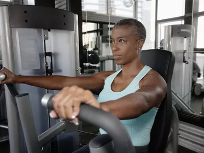 A woman using a chest press machine in a gym