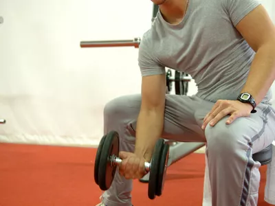 man doing dumbbell curls in gym