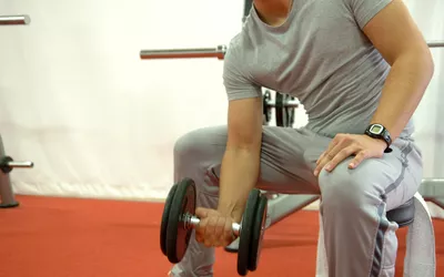 man doing dumbbell curls in gym