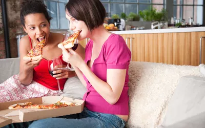 two women eating pizza and drinking wine