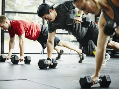 Group of friends doing pushups with dumbbells 