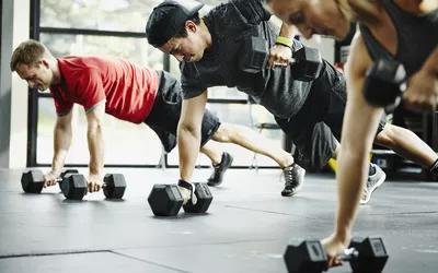 Group of friends doing pushups with dumbbells 