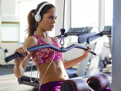 woman doing a lat pulldown and listening to music