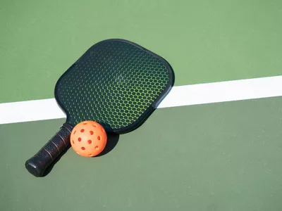 Pickle ball and paddle on court