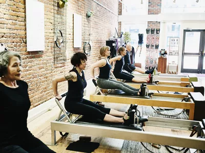 Group of pilates students doing tricep dips on reformers during class in fitness studio
