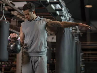 Young handsome mixed race Boxer Fighter training hard with a kettlebell in Gym