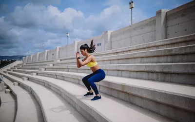 woman on stairs doing squat jumps