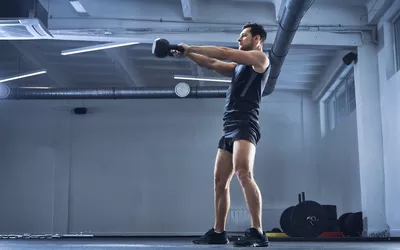 Athletic man doing kettlebell swing exercise at gym