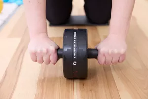 hands on handles of the Vinsguir Ab Roller in use on wood floor