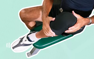 Person holding their knee clad in a knee brace outlined in white and displayed on a blue striped background 