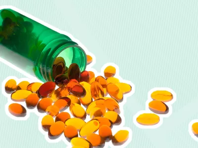 Vitamin D supplement bottle laid on its side with pills spilling out outlined in white on a striped background 