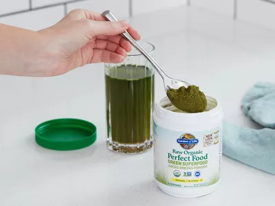 Hand holding a spoon full of Garden of Life Raw Organic Perfect Food Green Superfood powder