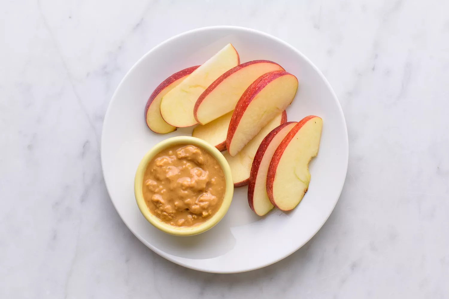 apple slices and chunky peanut butter on a plate