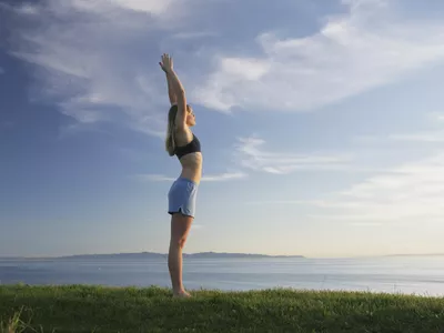 Woman doing yoga on a grassy bluff