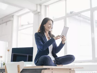 Businesswoman sitting on desk in a loft using tablet